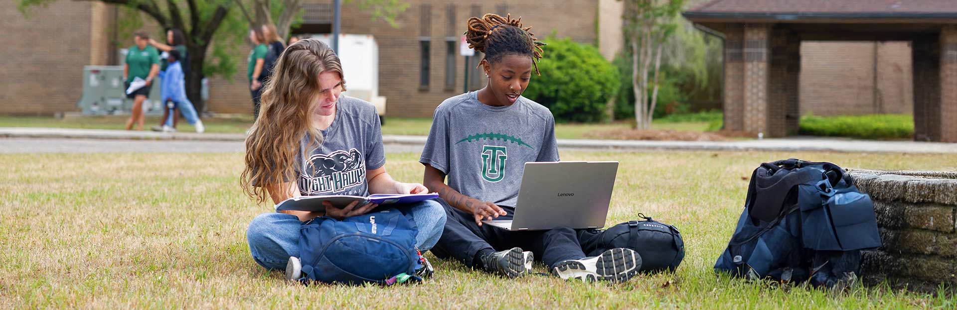 Two female students sitting on the lawn at Thomas University's new Woodlands Campus
