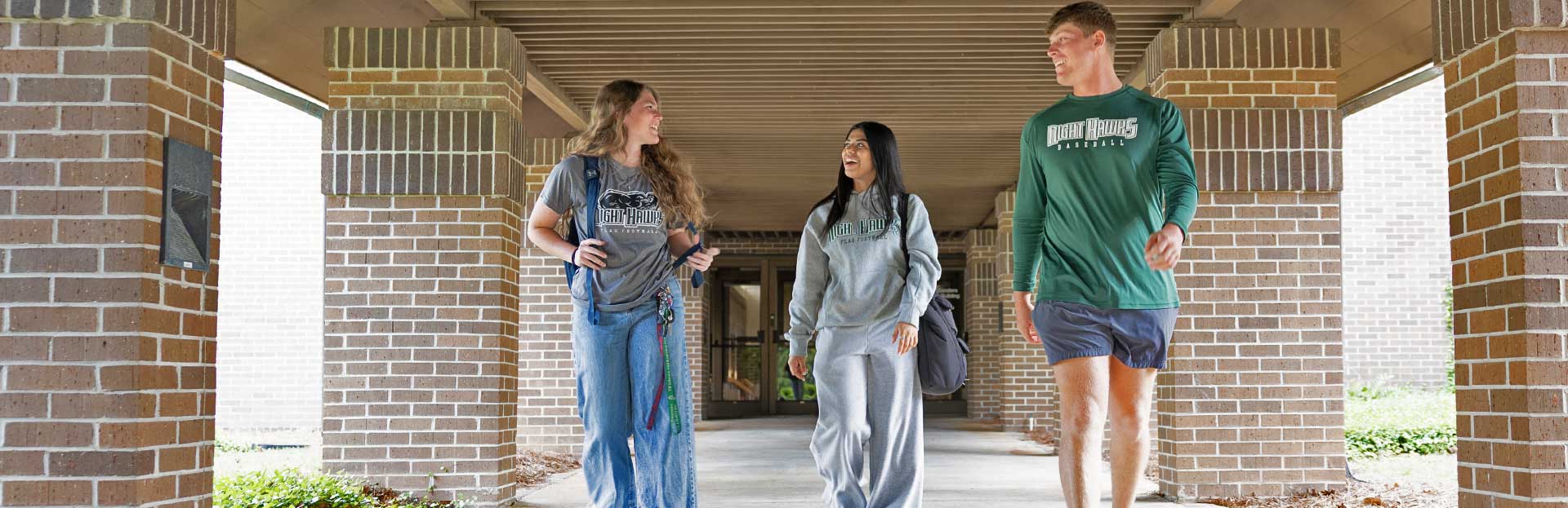 Two female and one male student exiting a building at Thomas Unversity's new Woodlands Campus